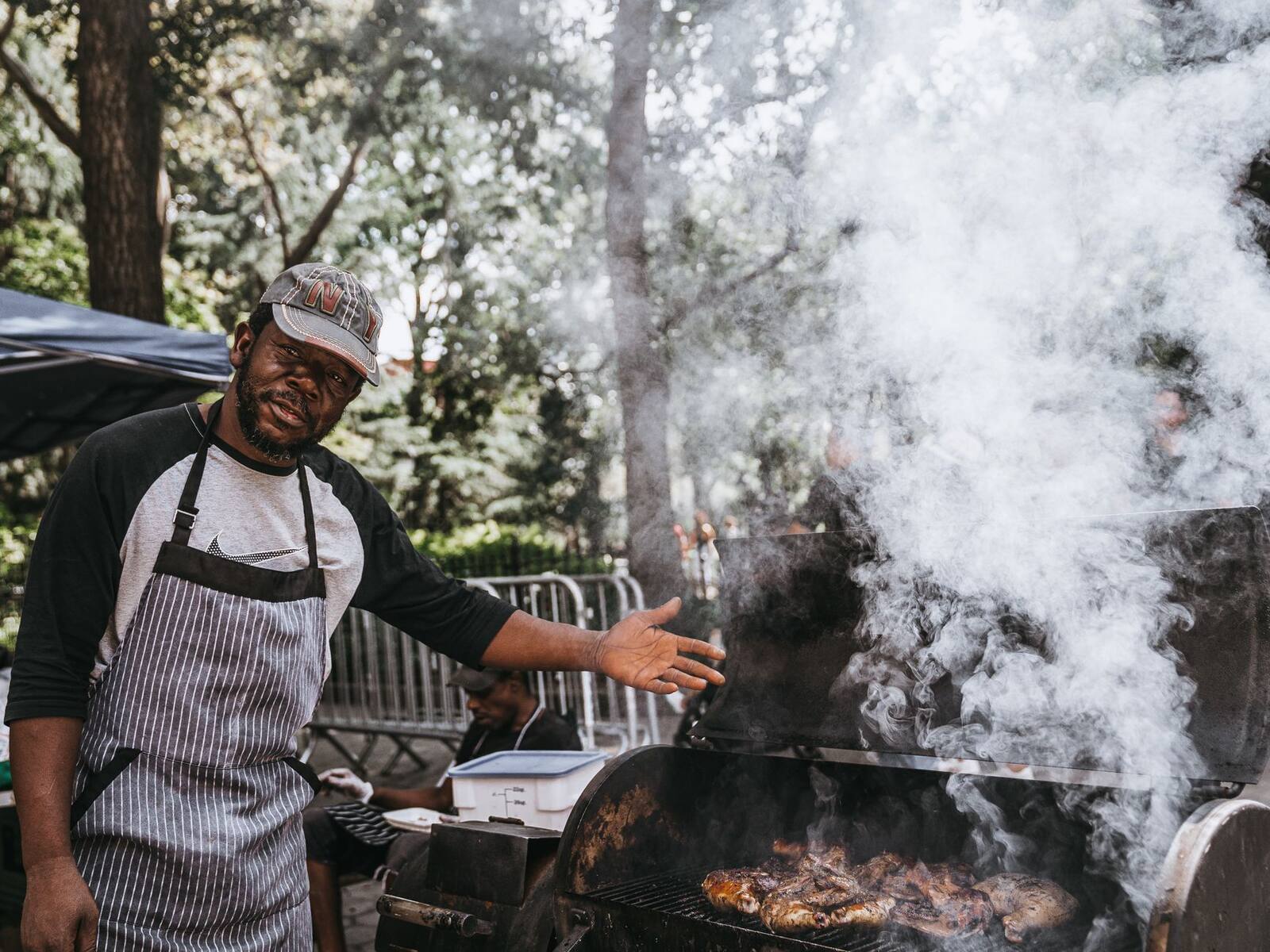 Jerk chicken cooking over an open flame grill, char and smoke rising